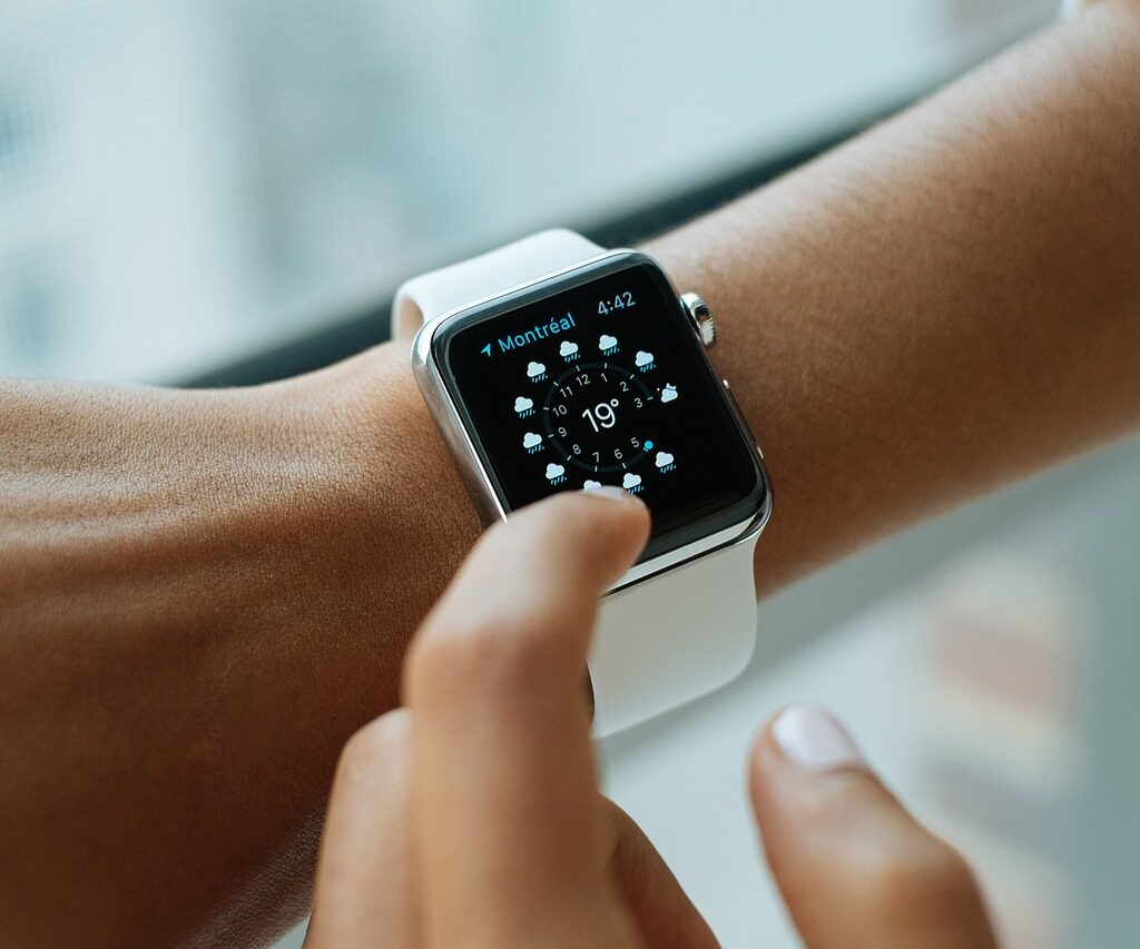  A person's hand using a white watch with a cloudy weather forecast.